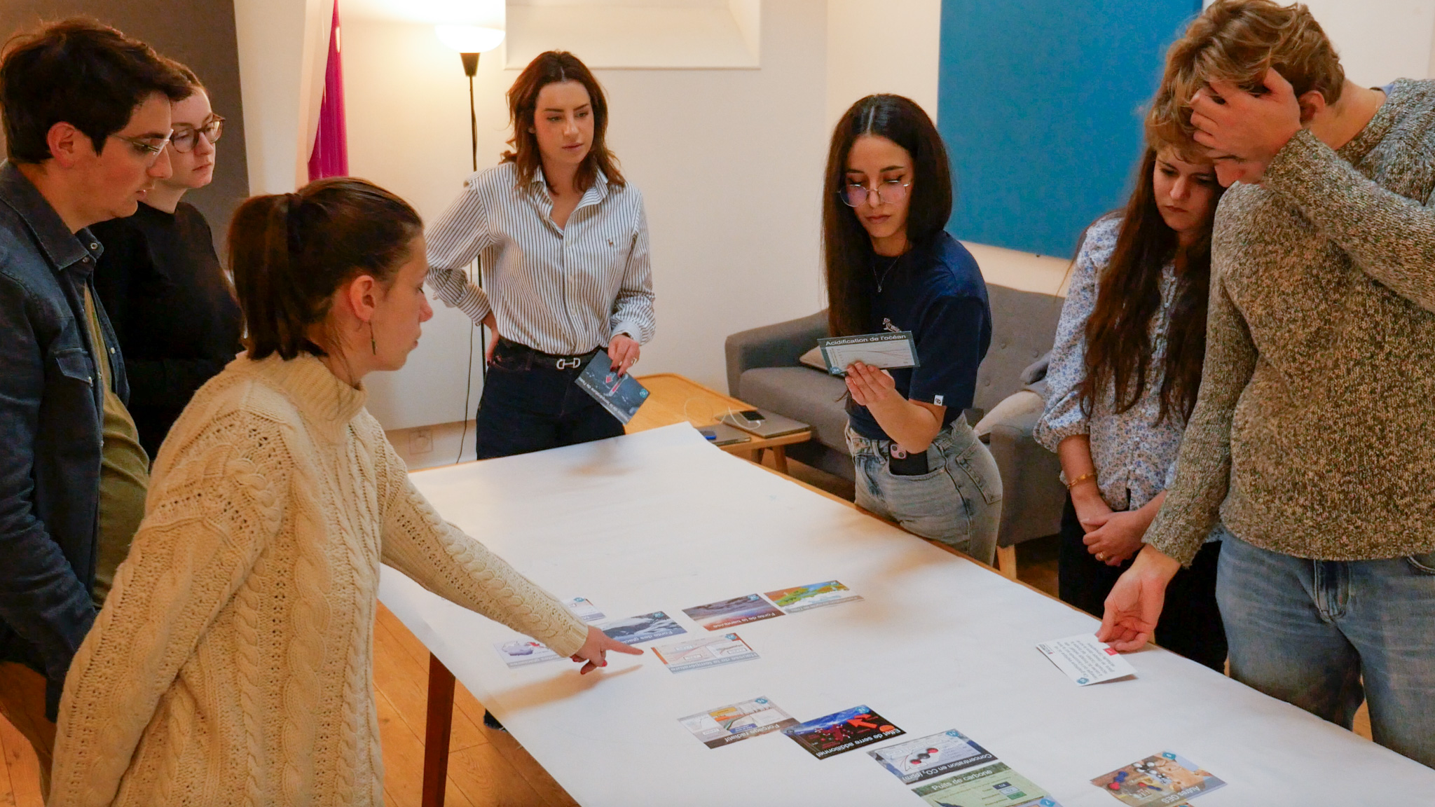 A team of Numberly employees standing around a table, looking at a card game explaining climate change