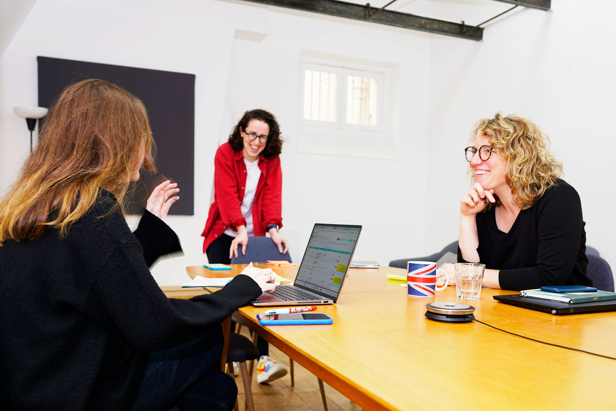 Three Numberly team members working around a table together, smiling